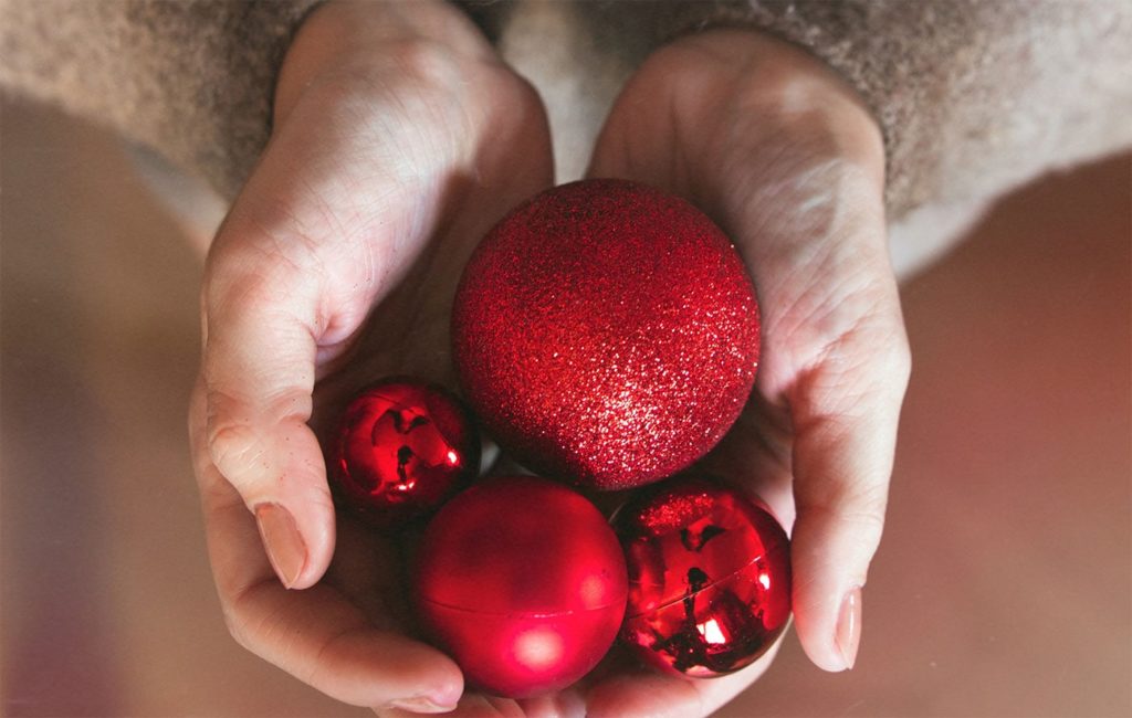 top down view of two hands holding red ball ornaments