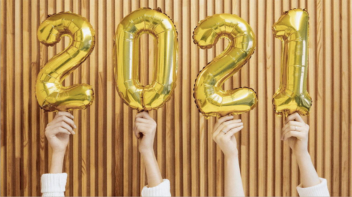 Hands holding up gold balloons of the numbers