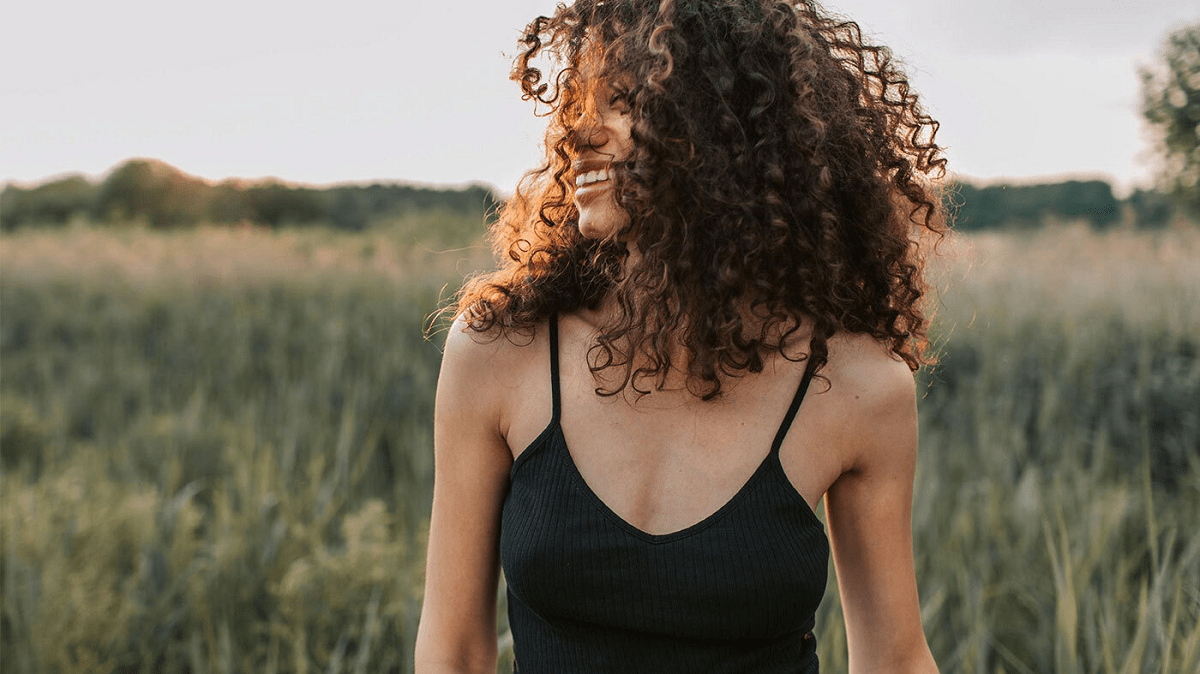 a woman smiling in a field of grass