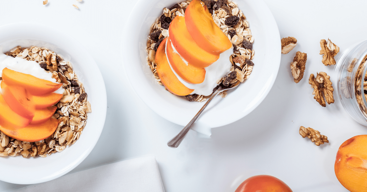 Top down view of bowls of granola, yogurt and peaches