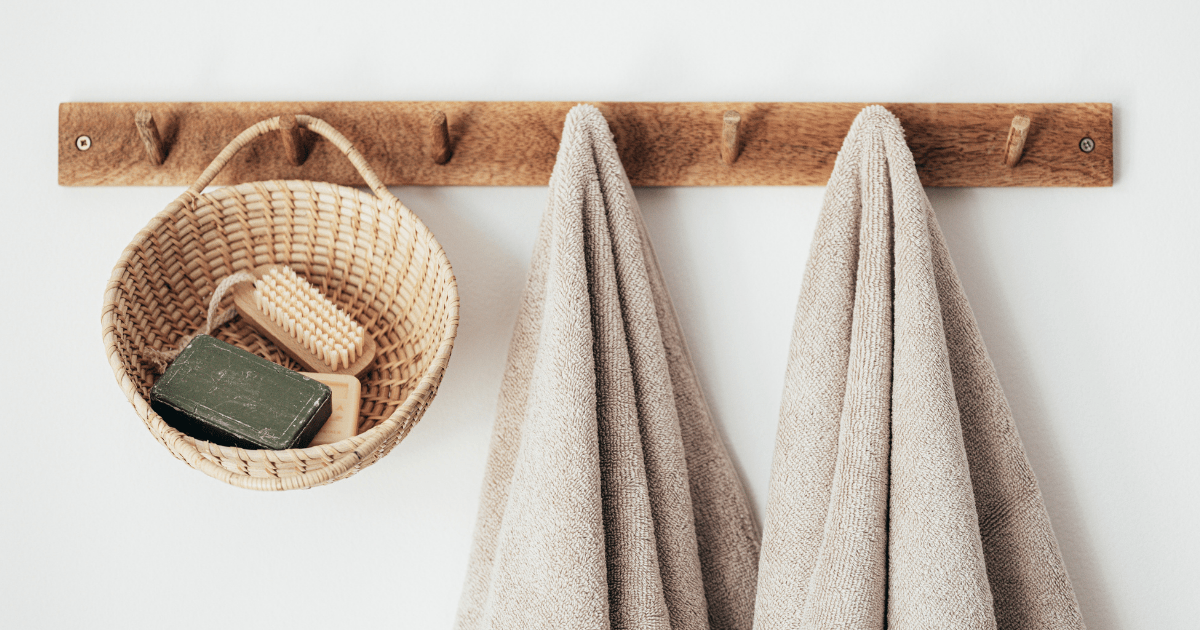 wooden hooks with a basket of shower essentials and two towels hung up