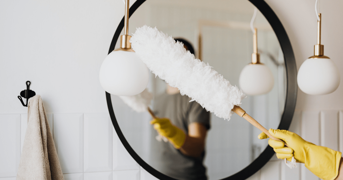 one gloved hand dusting hanging lights and a round mirror