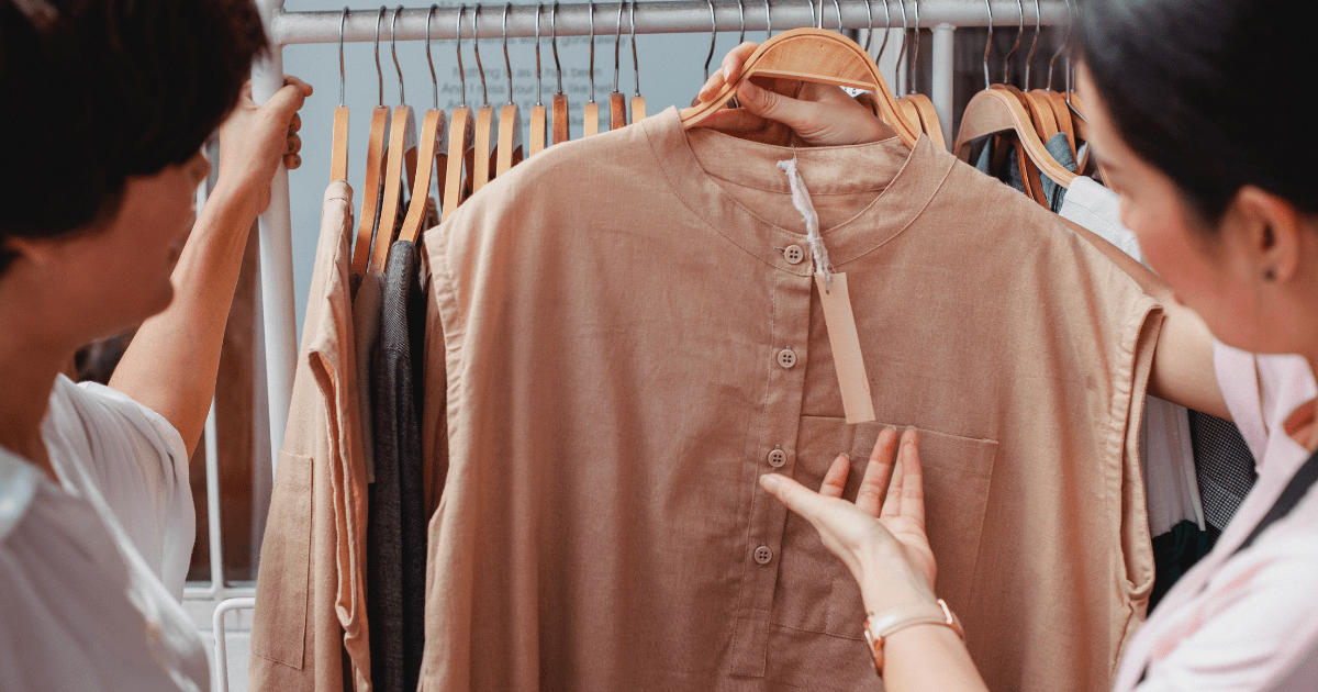 two people taking a shirt off of a clothes rack and looking at it together