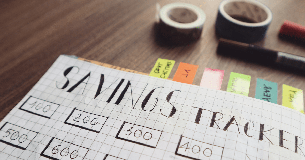 top down view of a handmade savings tracker with tape and markers next to graph paper
