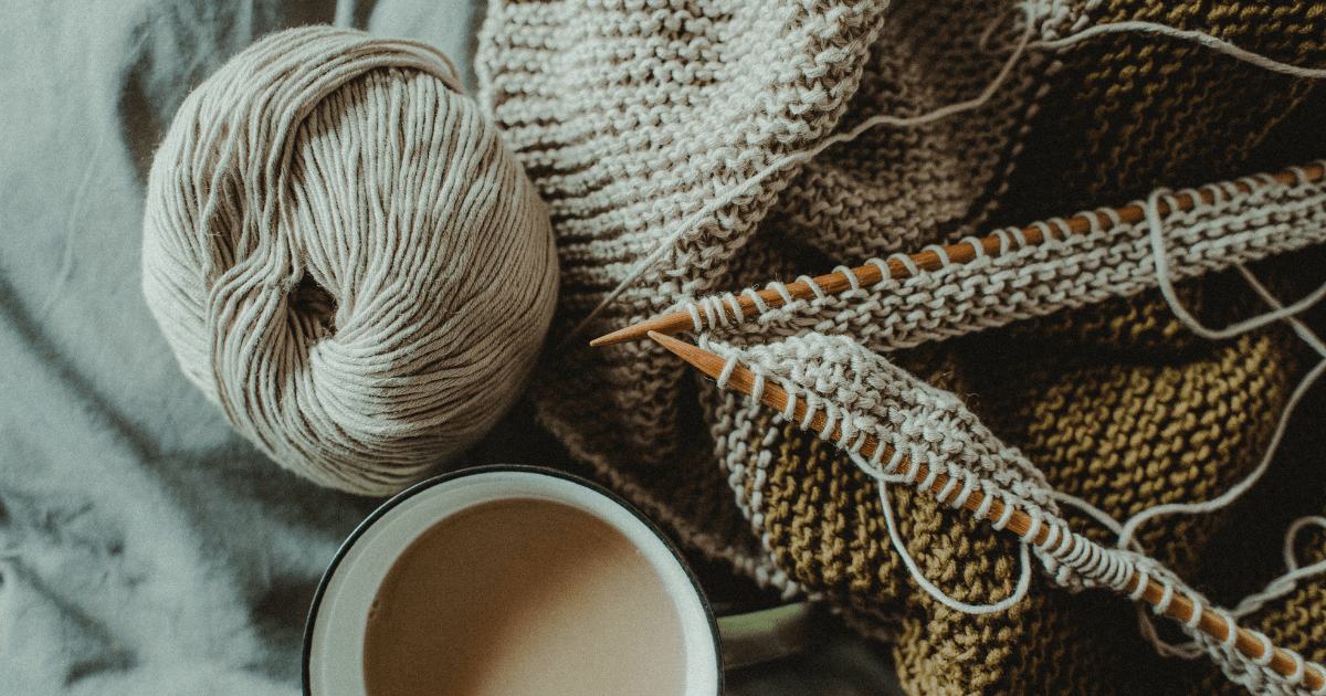 top down view of yarn, knitting needles, and knitted sweater