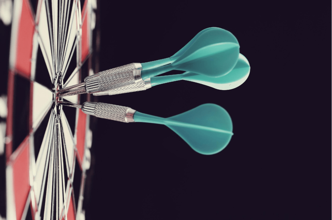 side view of a dart board and three darts on the bullseye