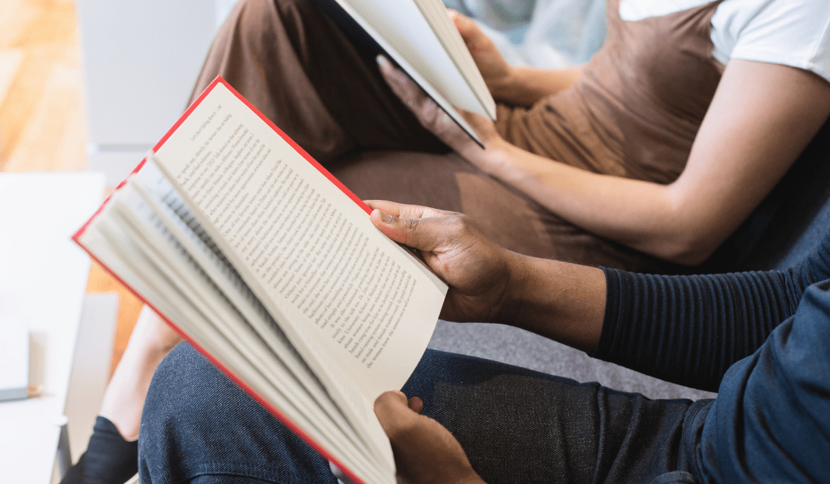 two people sitting side by side each holding an open book