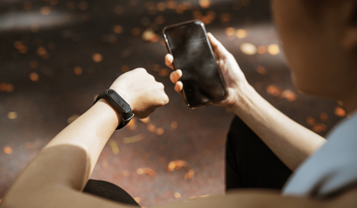 over the shoulder view of someone checking their watch and holding a smartphone