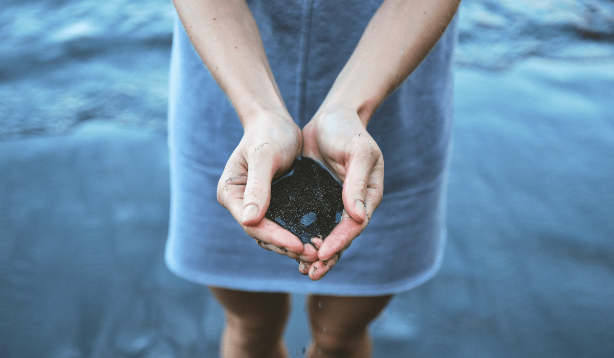 top down view of hands holding sand in water