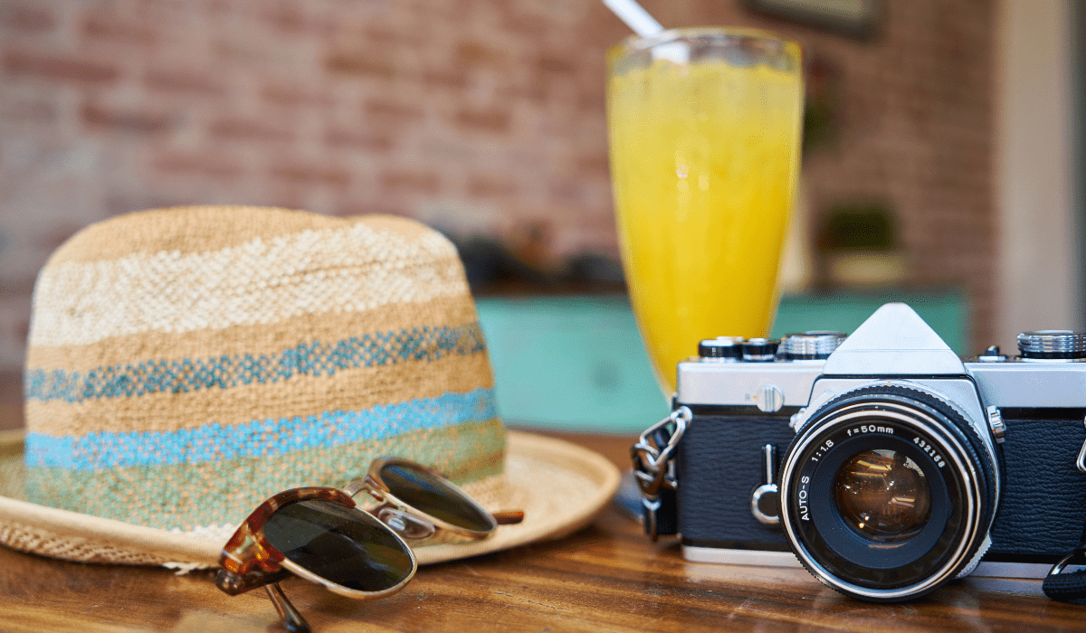 hat, sunglasses, old style camera and tropical drink