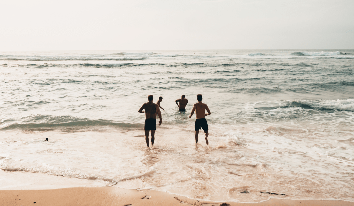 four people running into waves in the ocean
