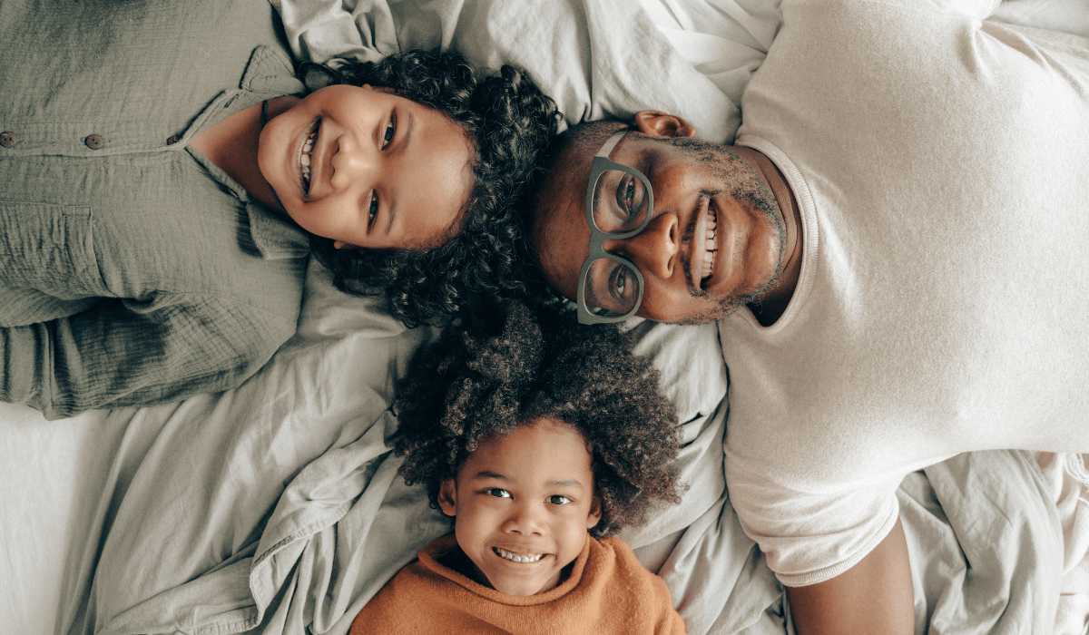 top down view of a man and two kids smiling up a the camera