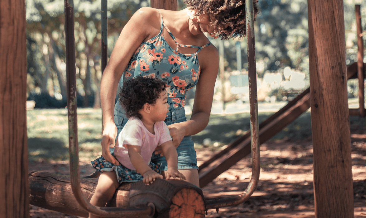 woman supporting a toddler on a wooden swing