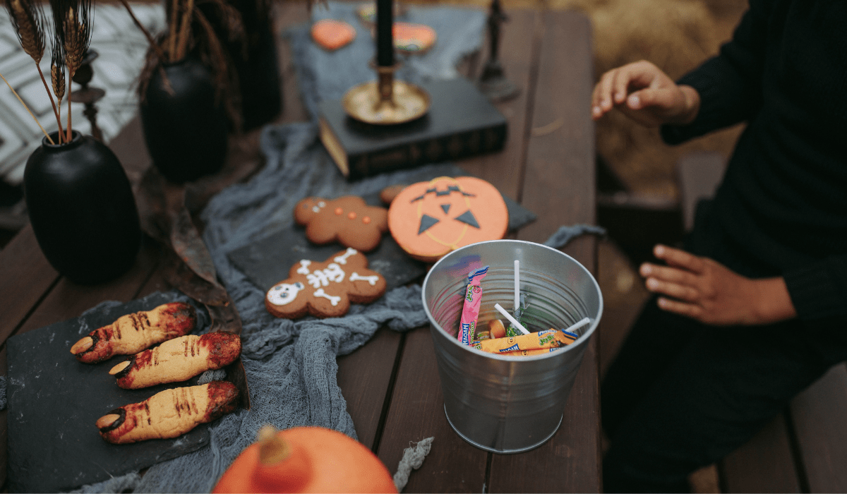 candy in a bucket, and halloween cookies on a wood picnic table