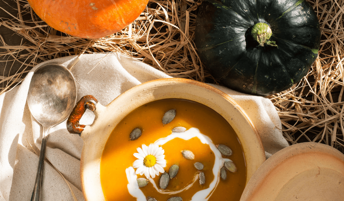 top down view of a bowl of pumpkin soup and two squashes