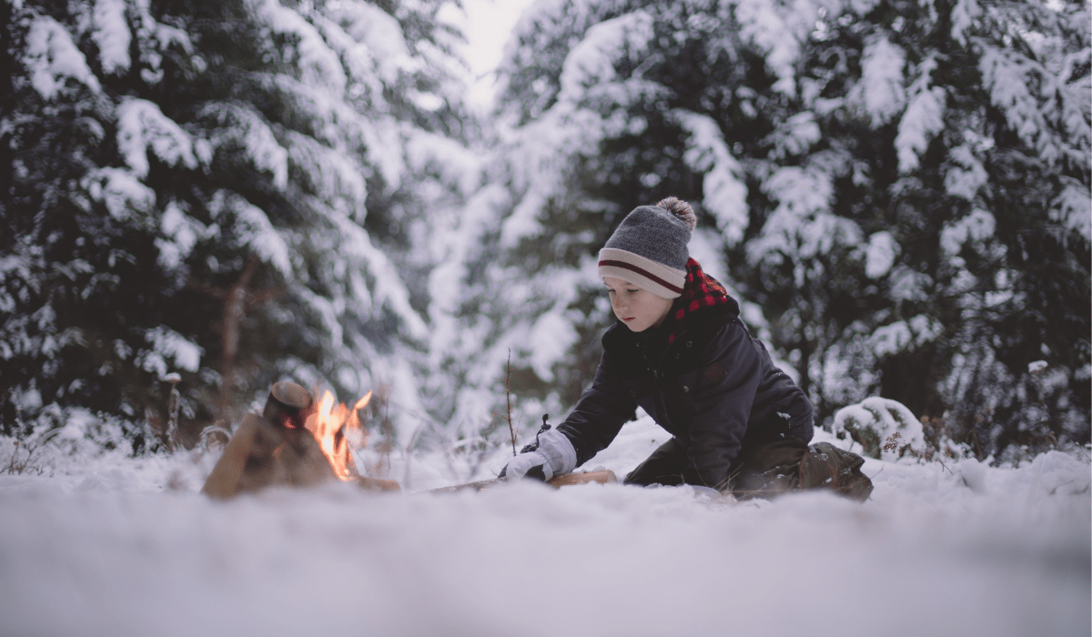 kid in the snow building a fire