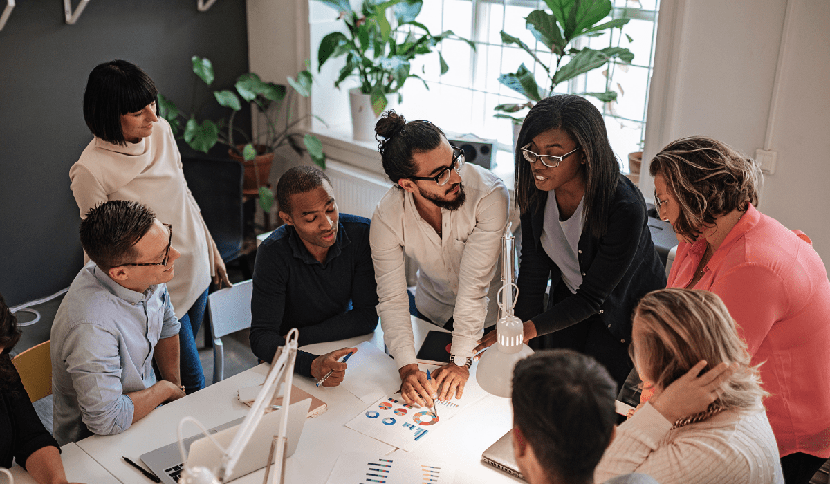 A group of people around a table looking over graphs and data working together