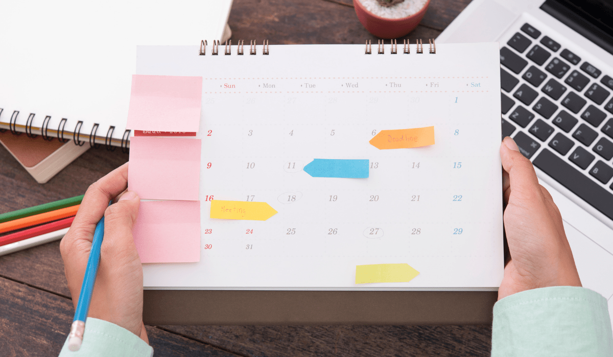A top down view of hands holding a paper calendar with sticky notes
