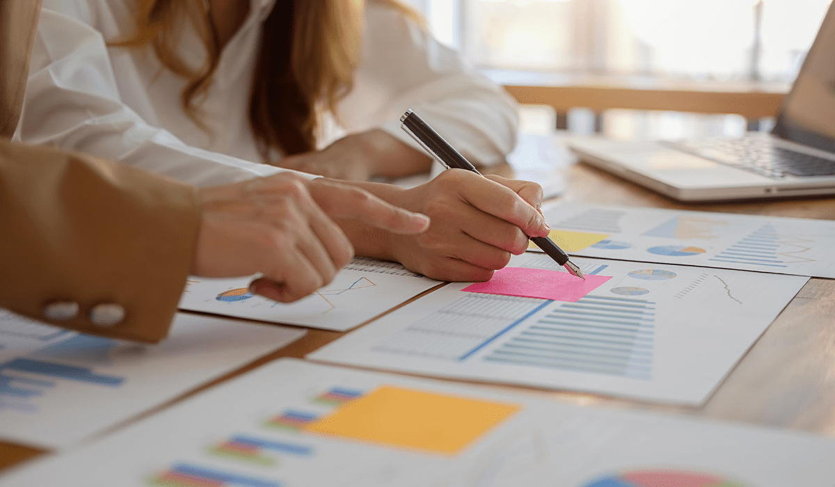 Close up of hands working over a table covered in graphs and charts
