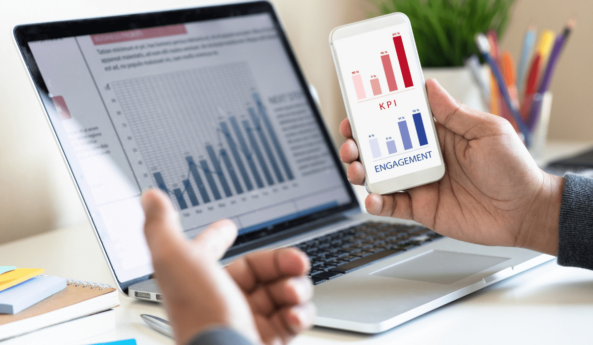 A laptop and mobile phone both have bar graphs of data up on the screen