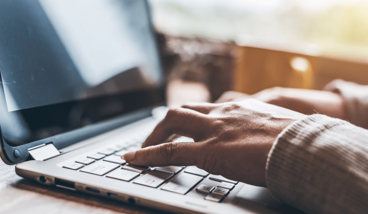 A close up of hands typing on a laptop keyboard