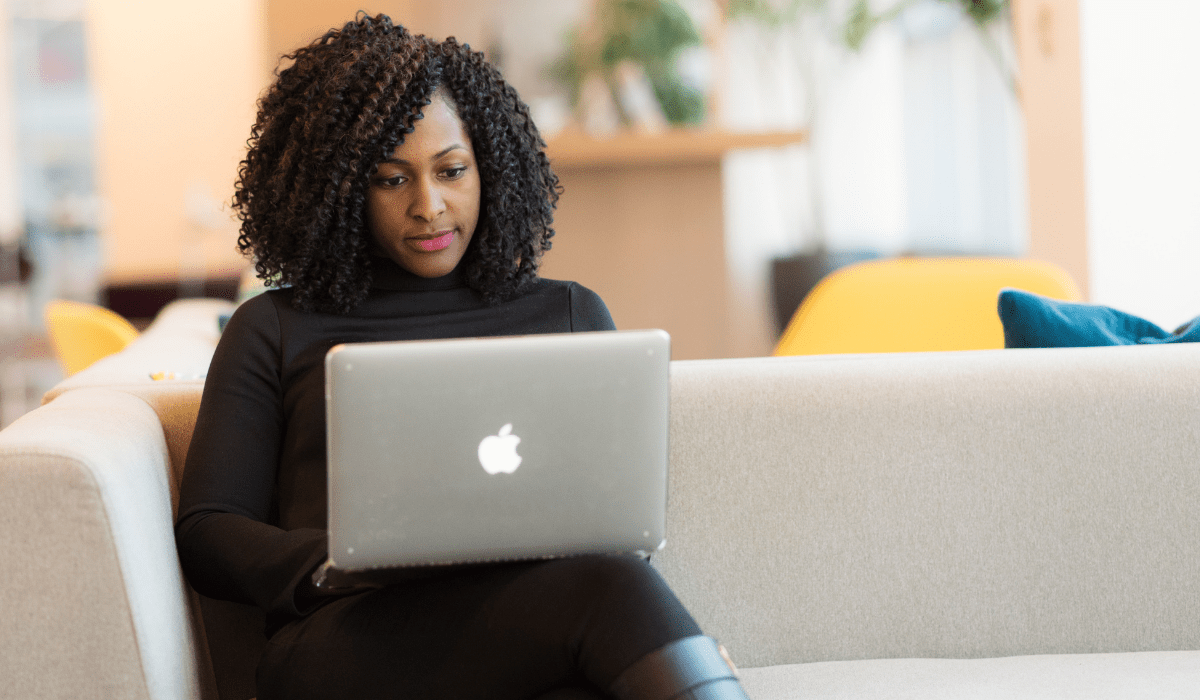 A woman sitting on a couch working on a laptop