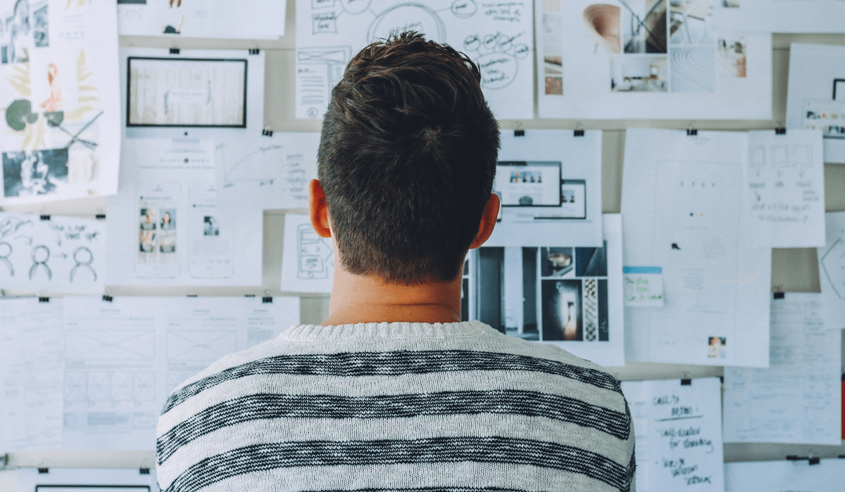 A person looking at a wall of papers pinned up