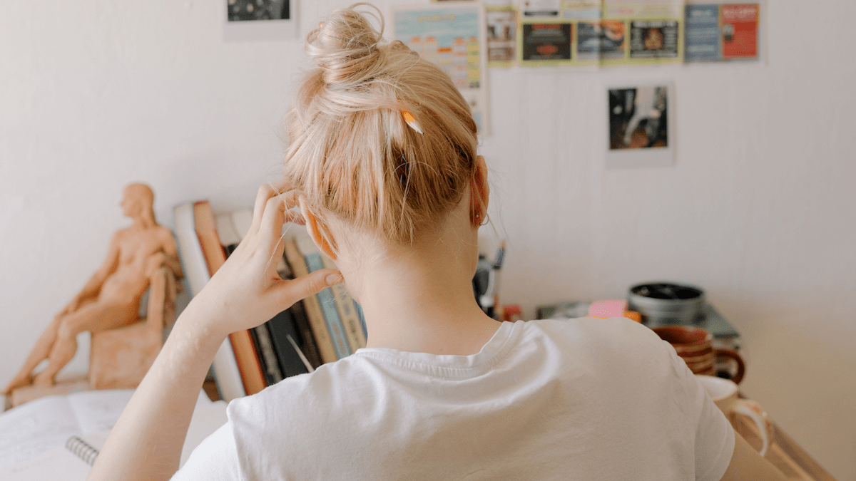 Back view of a person with fingers to their head working at a desk