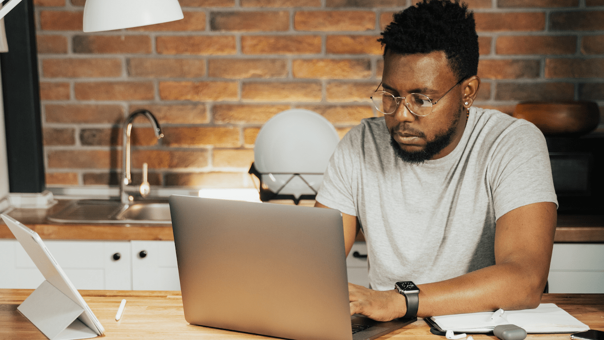 Person working at a wood desk on laptop with brick background